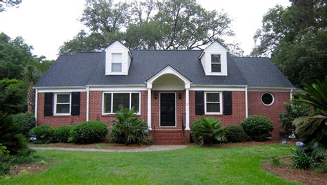 white brick house with red metal roof|black shingles on brick house.